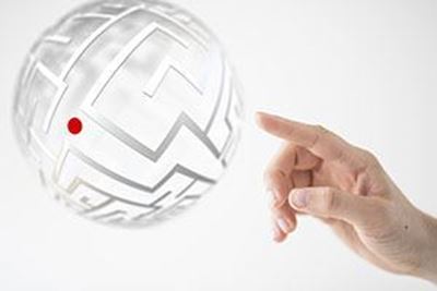 	finger pointing at crystal globe with a maze on it